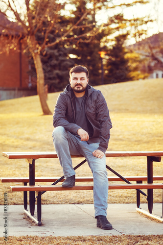 Young bearded man sitting on bench