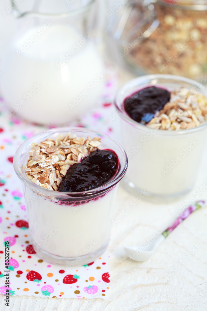 Small jar with homemade yogurt with blackcurrant jam and granola Small jar with homemade yogurt with blackcurrant jam and granola