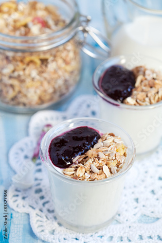 Small jar with homemade yogurt with blackcurrant jam and granola