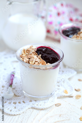 Small jar with homemade yogurt with blackcurrant jam and granola