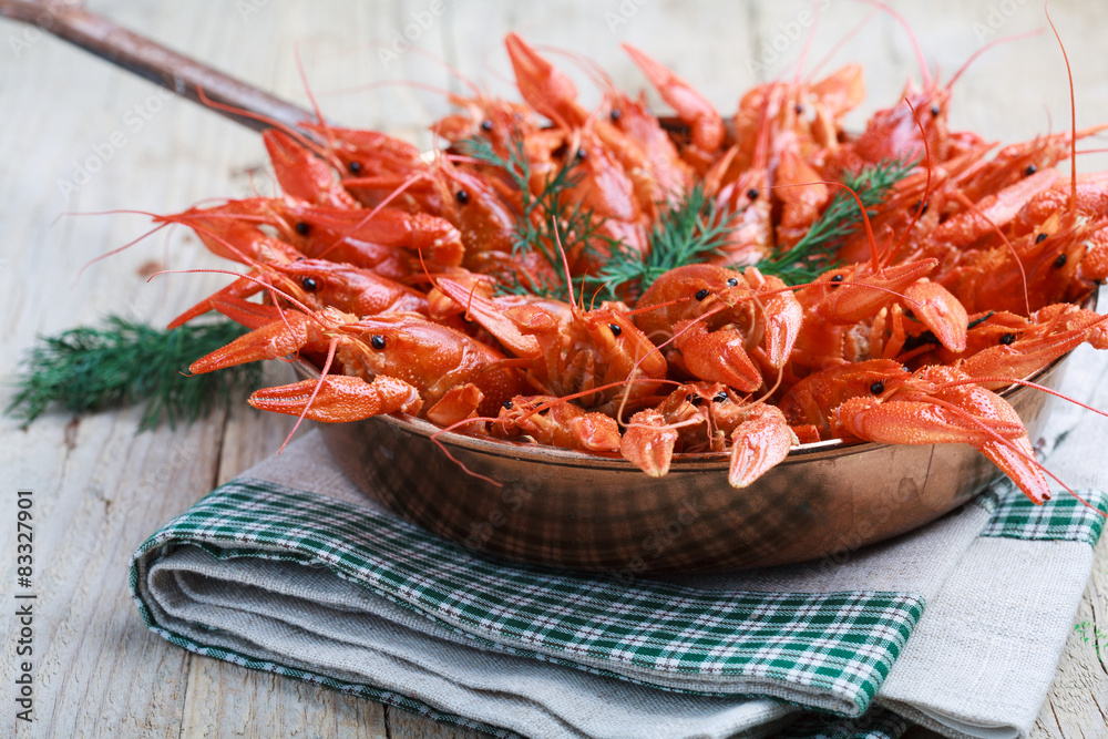 Copper frying pan with red boiled crawfish on a wooden table Copper frying pan with red boiled crawfish on a wooden table