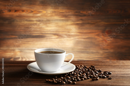 Cup of coffee with grains on wooden background
