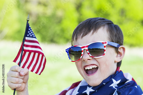 4th of july holiday: happy boy in sunglasses holding  American flag 