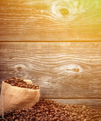 Sack of coffee grains against wooden background