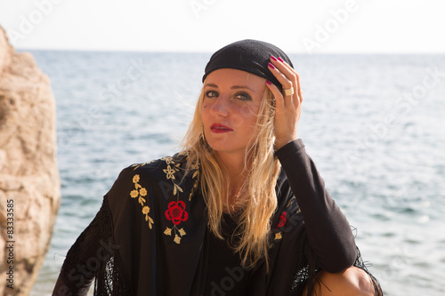 Young gypsy meditating on the rocky beach