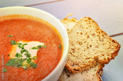 Tomato soup with basil and fresh black bread closeup