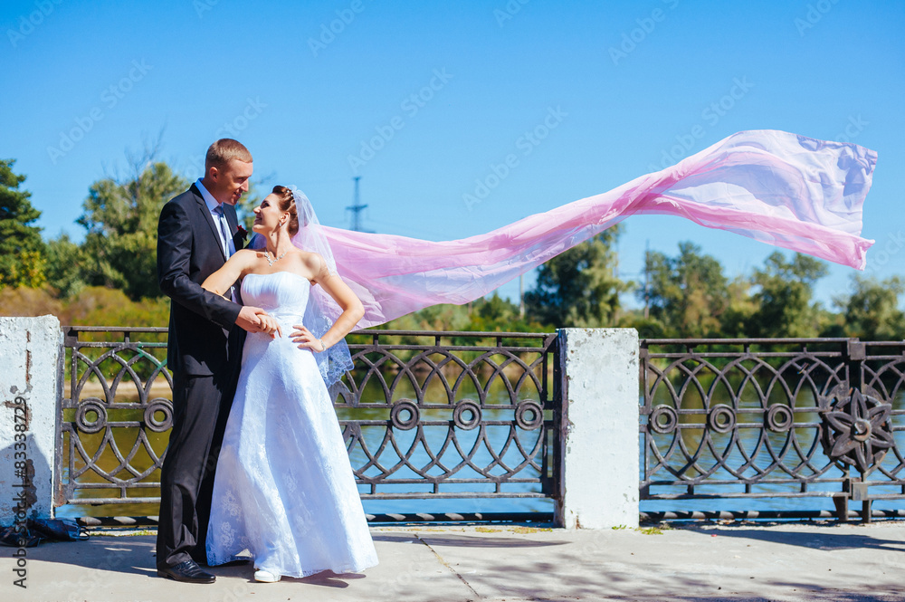 newly married couple.wind lifting long white bridal veil. bride
