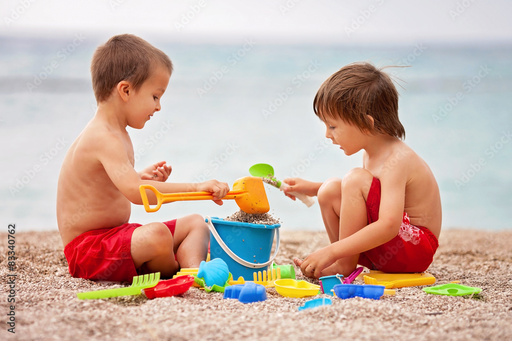 Two cute kids, playing in the sand on the beach Two cute kids, playing in the sand on the beach