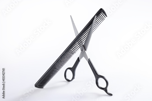 Scissors and comb standing on a table isolated