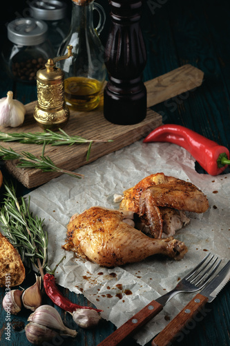 Roasted chicken with spices and herbs on a wooden table.