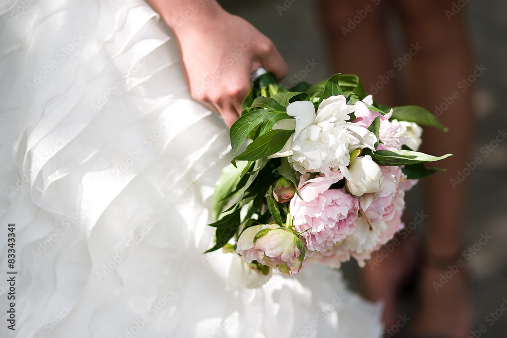 Gentle wedding bouquet with peonies in hands of the bride Gentle wedding bouquet with peonies in hands of the bride