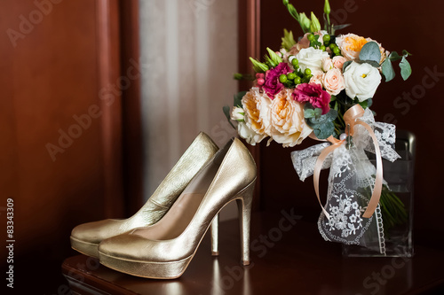 Golden wedding shoes and gentle bridal bouquet with lace bow