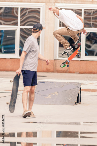 handsome guys riding by skateboard at freestyle park outdoors