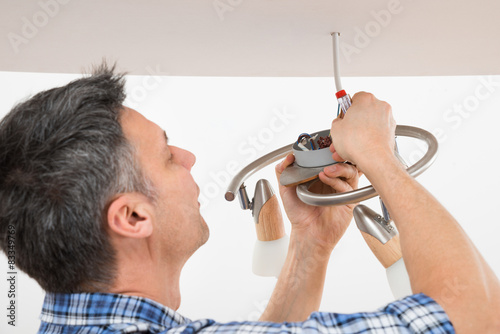 Electrician Fixing Light On Ceiling