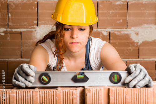 Woman Bricklayer Holding a Spirit Level on a Brick Wall