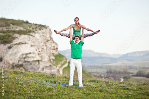 Acroyoga. Woman and man doing yoga on mountain