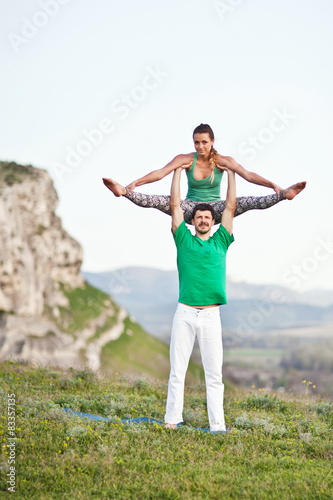 Acroyoga. Woman and man doing yoga on mountain