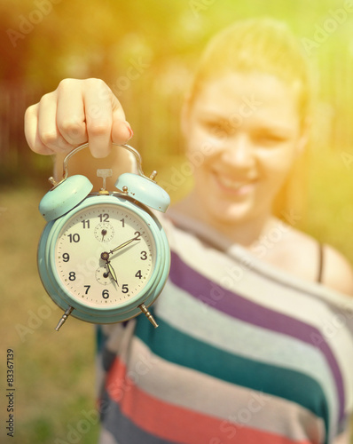 Teenage girl holding vontage clock outdoors with focus on clock photo