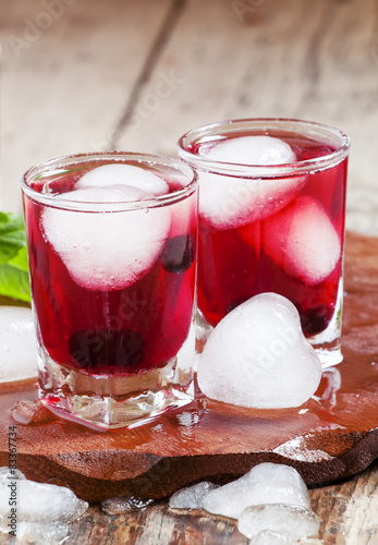 Red berry juice with ice in the shape of hearts, selective focus