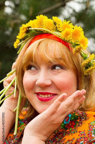 Cheeked Russian cheerful young woman in a wreath of fresh dandel