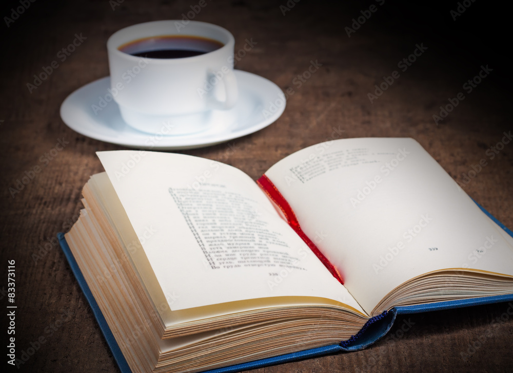 Open book with a cup of coffee on wooden table Open book with a cup of coffee on wooden table