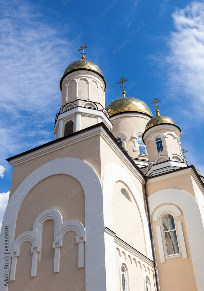 Golden domes of Russian orthodox church with cross against blue