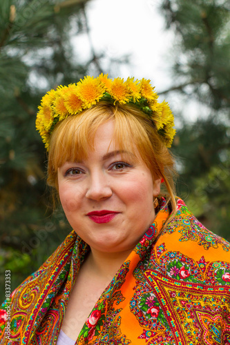 Cheeked Russian cheerful young woman in a wreath of fresh dandel photo