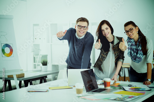 Young business people standing at office near desk and showing