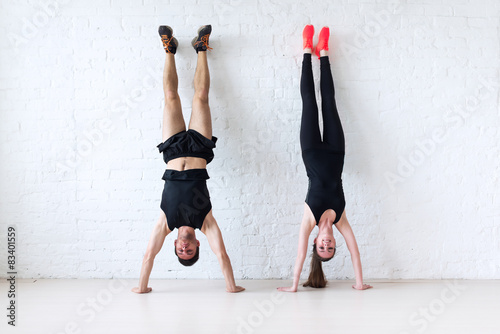 Valokuvatapetti sportsmen woman and man doing a handstand against wall concept