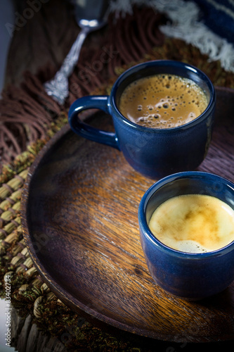 Two blue cups of espresso on wooden plate