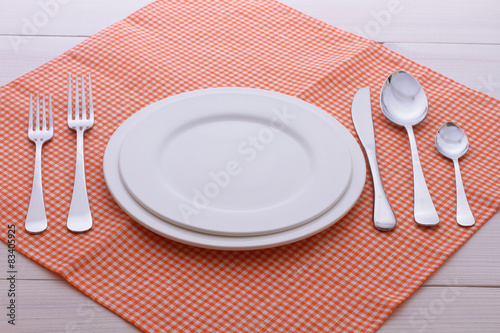 Empty plates, cutlery, tablecloth on white table for dinner. photo