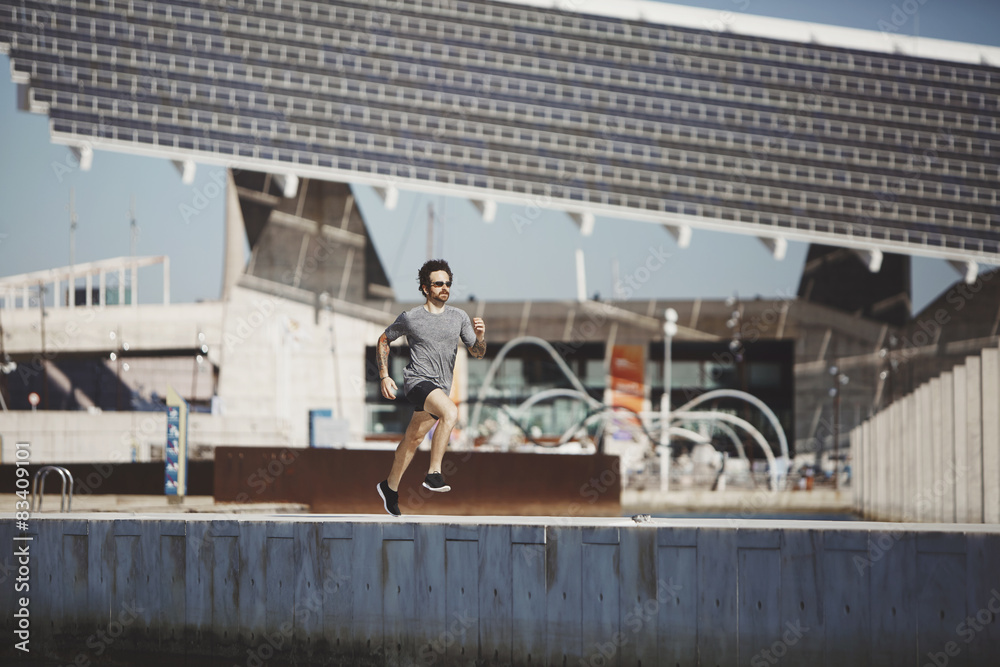 Naklejka premium Athlete runner training at road in sportswear at central