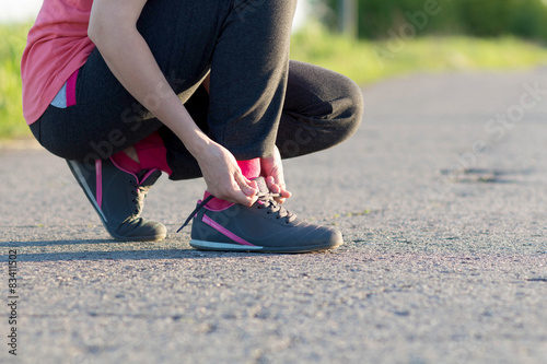 Girl tying shoelaces shoes sitting on the asphalt road