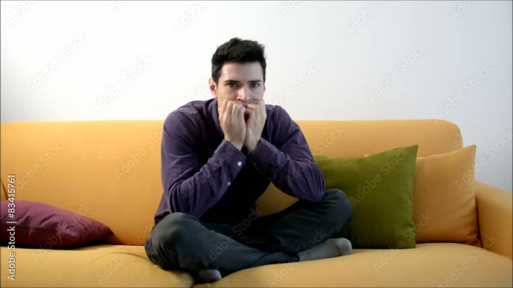 Young man on couch watching TV, changing channels scared Young man on couch watching TV, changing channels scared
