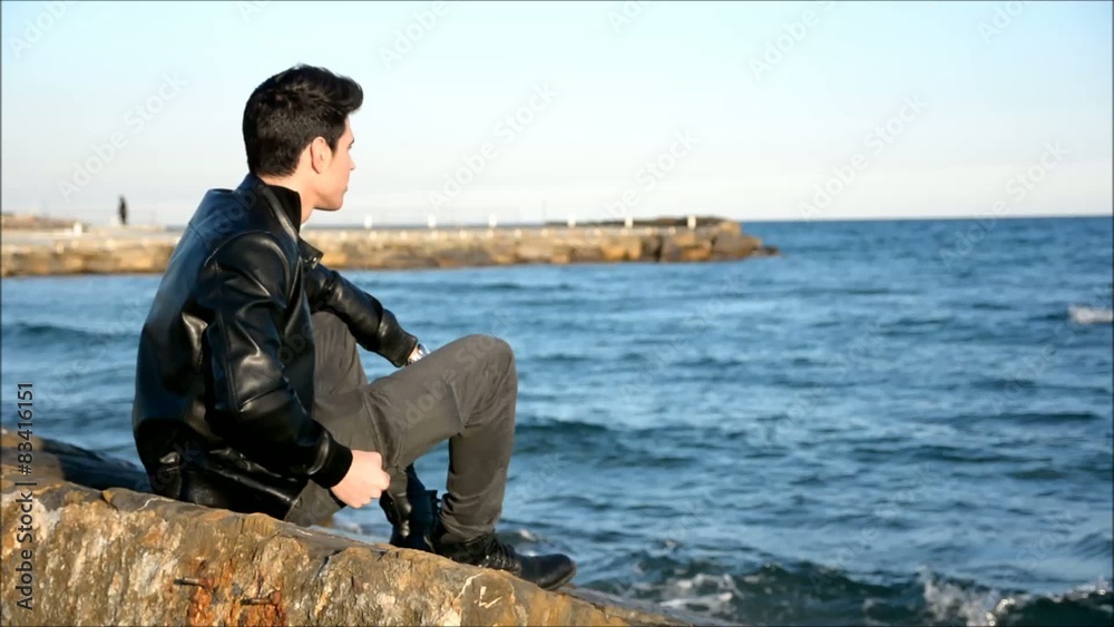 Young man at the seaside overlooking the ocean or sea Young man at the seaside overlooking the ocean or sea