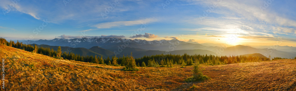 Panoramic view of mountain range and sunset meadow
