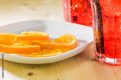 spritz aperitif cocktail with ice cubes near plate oranges photo