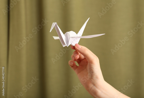 Female hand with paper crane on blurred background