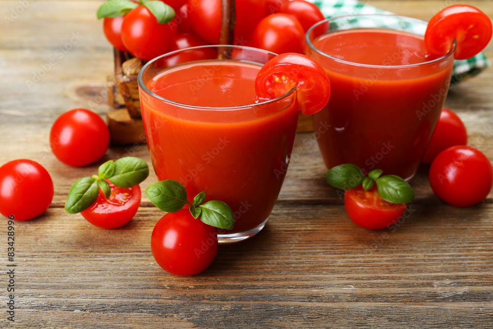 Glasses of tomato juice with vegetables on wooden background
