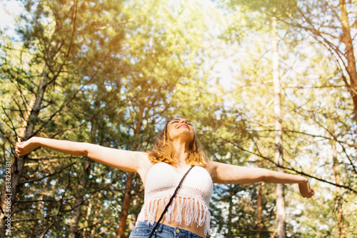 Relaxed boho woman with raised hands feeling free outdoors