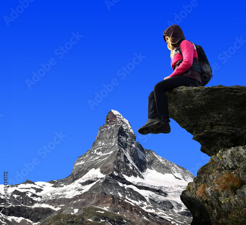 Girl sitting on a rock, in the background Matterhorn