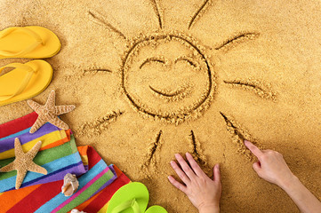 Summer beach smiling sun happy smiley face drawing drawn in sand with accessories holiday vacation photo