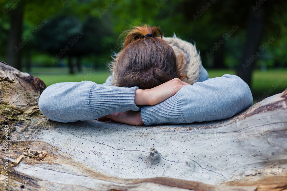 Sad woman resting on tree trunk Sad woman resting on tree trunk