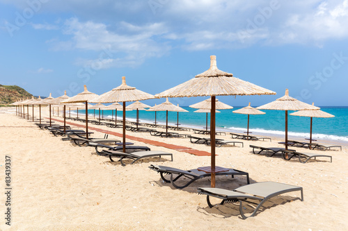 Many reed beach umbrellas in a row on empty beach at sea