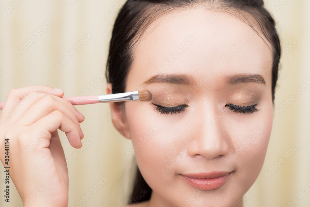 Portrait of pretty young woman applying cosmetic paint brush,mod Portrait of pretty young woman applying cosmetic paint brush,mod