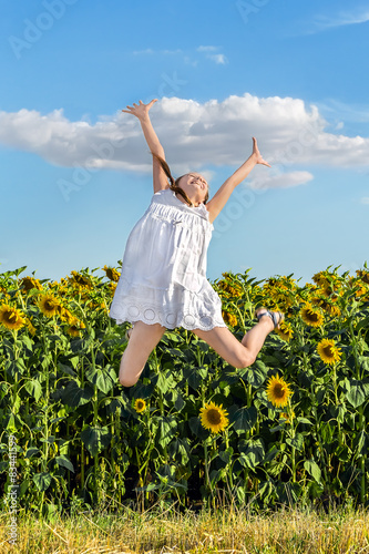 Girl jumping on a background of a field of sunflowers
