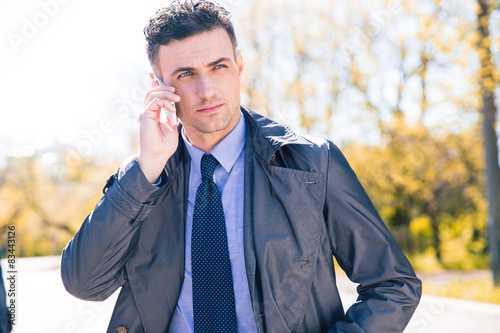 Confident businessman talking on the phone outdoors