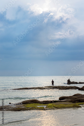 image of a fisherman who is standing alone at the seashore
