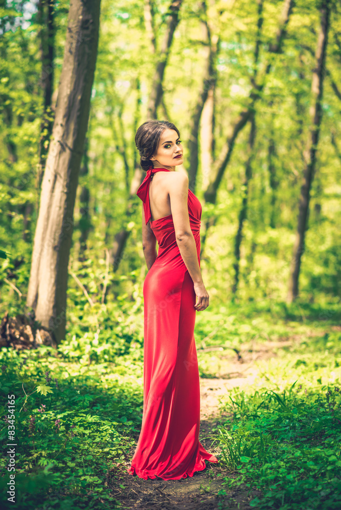 Woman in long red dress walking in the forest