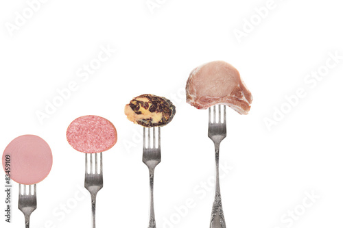 Pieces of different sausages and a piece of meat on the forks. I